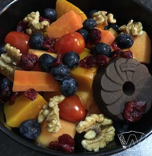 Bowl of carrot pumpkin blueberry dried cranberry cherry tomato walnuts dark chocolate cookie