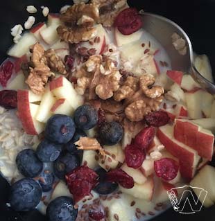 Bowl of milk with apple walnuts blueberry dried cranberry 