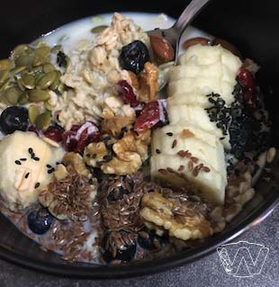 Japanese bowl of rolled oats  milk nuts pumpkin seeds sesame seeds   dried cranberries banana slices 