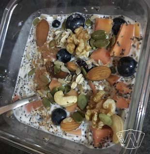 Square glass bowl of rolled oatss cashew nuts almond nuts pumpkin seeds papaya blueberry