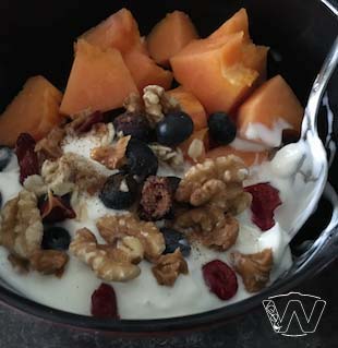 Bowl of milk yogurt papaya blueberry cranberry walnuts 