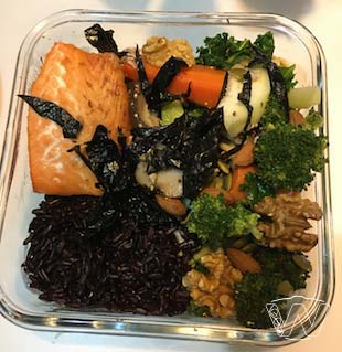 Square glass bowl of grilled salmon broccoli carrot walnuts and berry rice