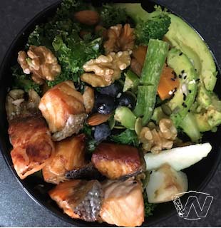 Bowl of golden glazed salmond cube-cuts avocado walnuts boiled broccoli green capisium 