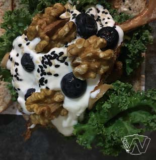 Wholemeal bread spread with yogurt toppings of kale walnuts blueberry of sesame seeds