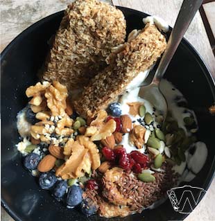 Bowl of yogurt with crispy weetbix biscuits topppings of blueberry almond nuts pumpkin seeds walnuts flaxseeds